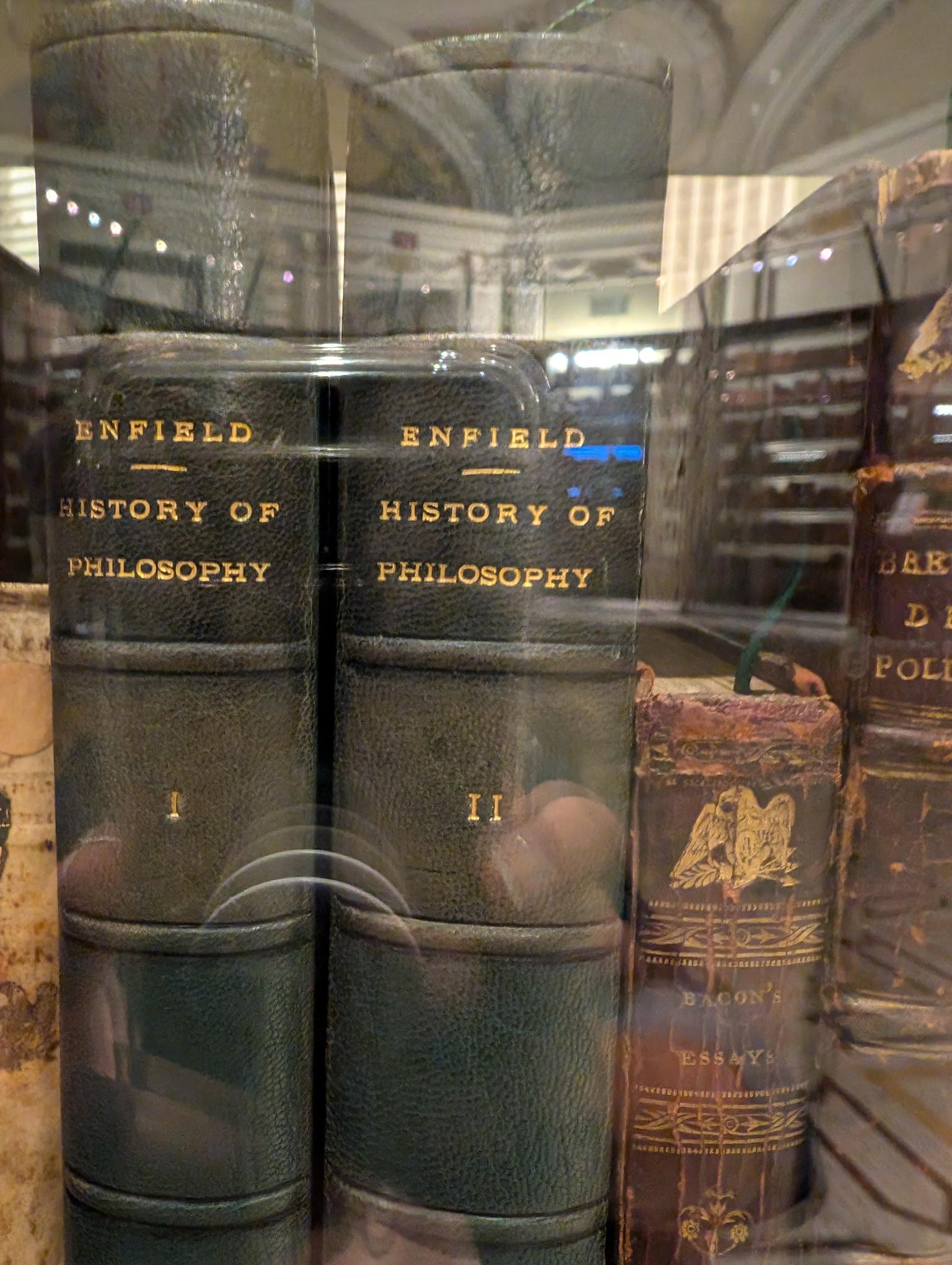 A few of Jefferson's books, photographed through glass. Visible titles are Enfield's History of Philosophy volumes I and II, and Bacon's Essays.