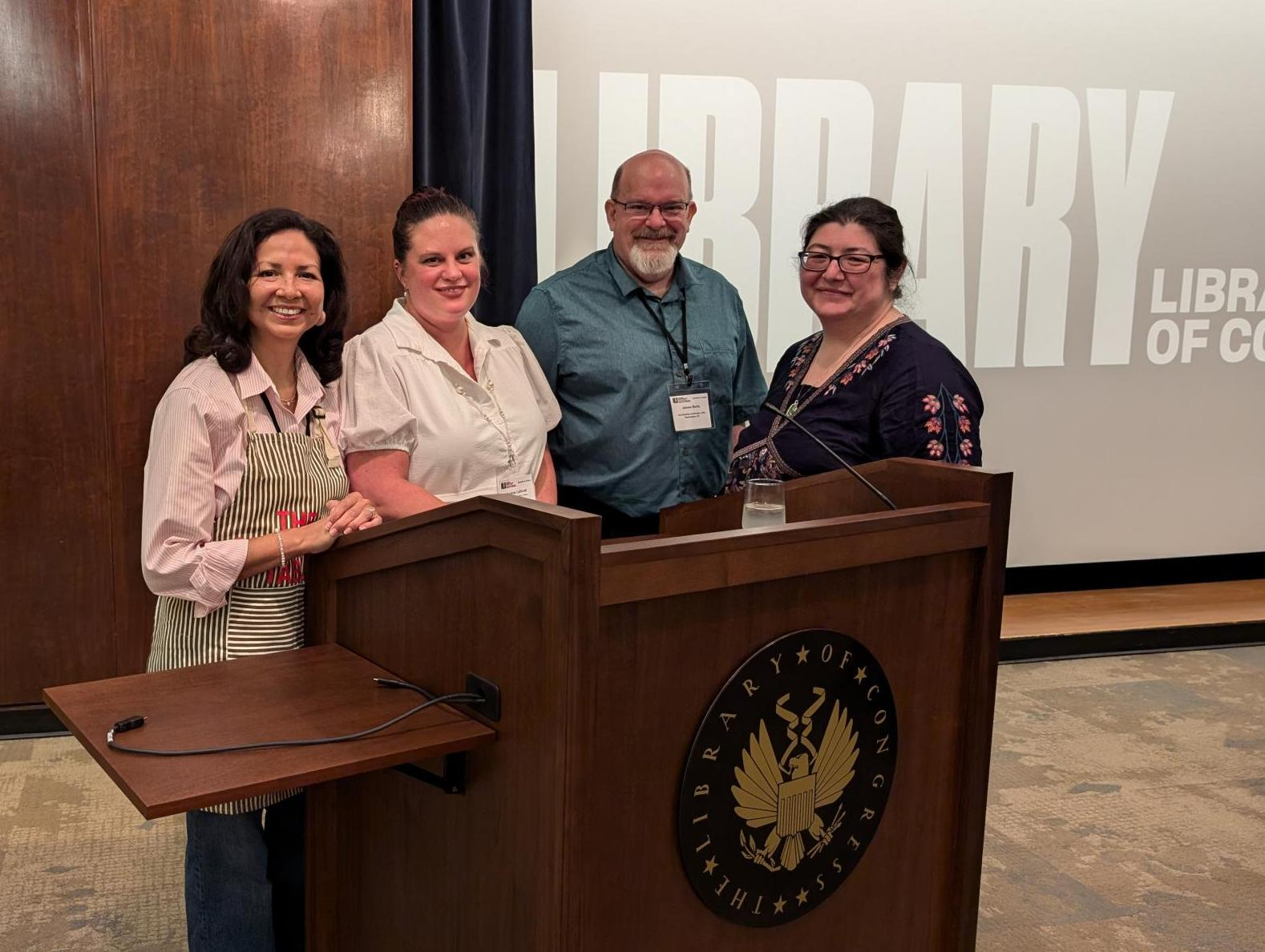 Maureen, Drea, James, and Mitake are gathered behind a podium with the Library of Congress' seal on the front.