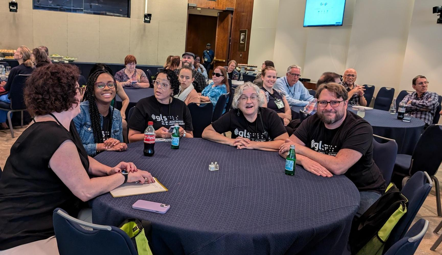 At a round table covered in a black table cloth five NLS conference attendees sit.